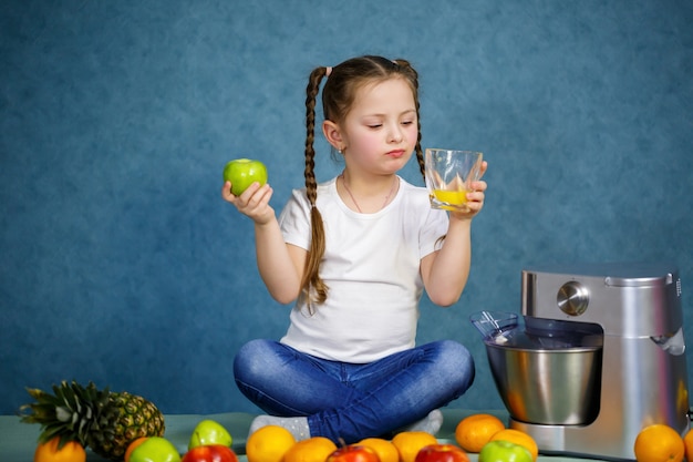 Une petite fille a pressé du jus de fruits frais de pommes et d'orange. Vitamines et alimentation saine pour les enfants.