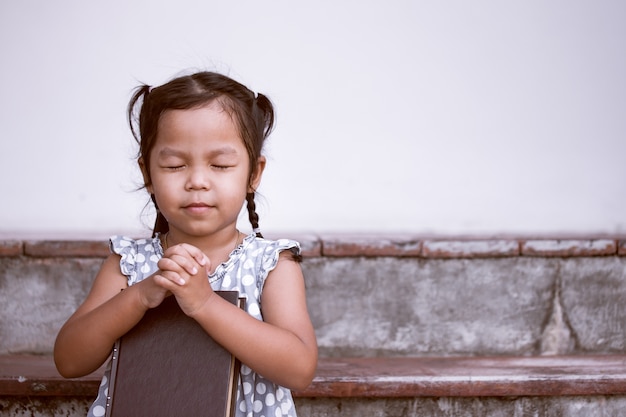 Petite fille prie avec une Sainte Bible