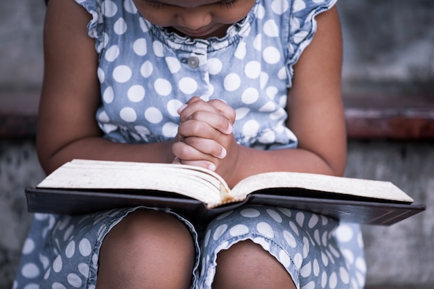 Petite fille prie avec une Sainte Bible