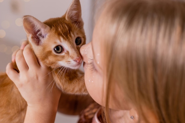 Une petite fille princesse vêtue d'une robe élégante tient un chaton rouge dans ses mains. Le symbole de l'année