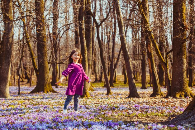 Petite fille profite du soleil, elle rêve et vole, inspirée par la prairie fleurie des safrans