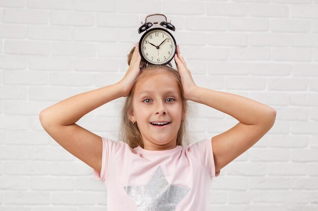 Petite fille en pyjama avec horloge