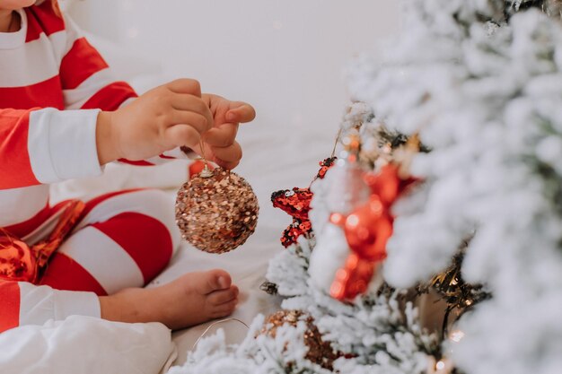 Petite fille en pyjama rayé de Noël décore le sapin de Noël. mode de vie. Photo de haute qualité