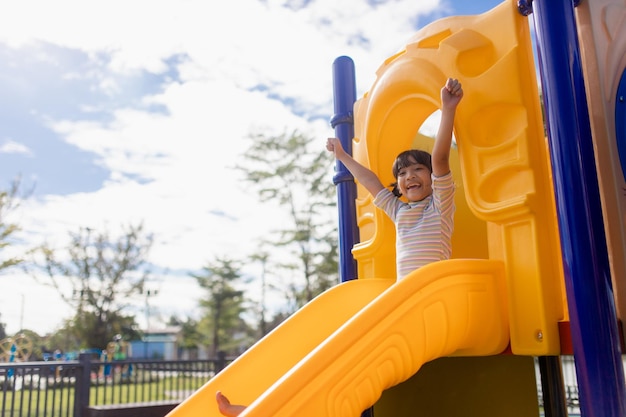 Petite fille qui descend le toboggan à l'extérieur du parc ou de l'aire de jeux