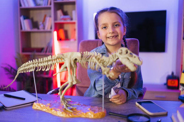 Une petite fille qui fait un modèle de tyrannosaure à partir d'os.