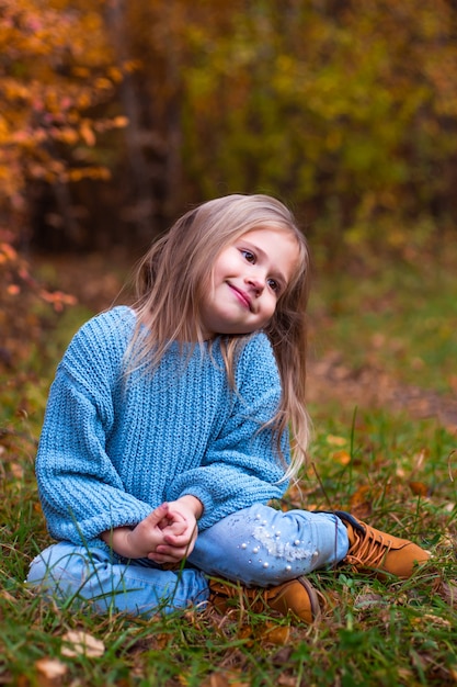 petite fille qui marche dans la forêt d'automne en vêtements blu