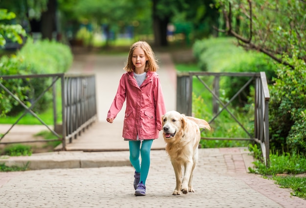 Petite fille qui marche avec golden retriever à l'extérieur dans le parc