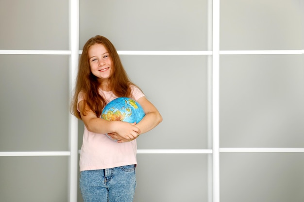 Une petite fille qui rit et tient un globe de physique.