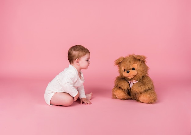 Petite fille rampant à côté d'un chien en peluche