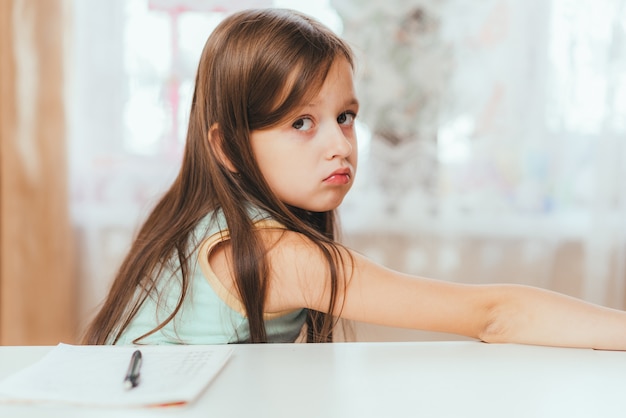 Une petite fille refuse de faire ses devoirs à la maison