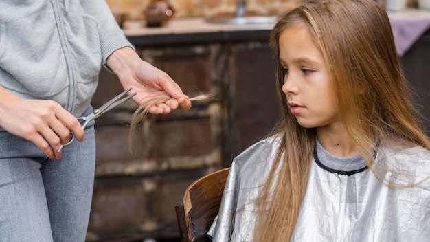 Petite fille regardant les cheveux coupés par le coiffeur