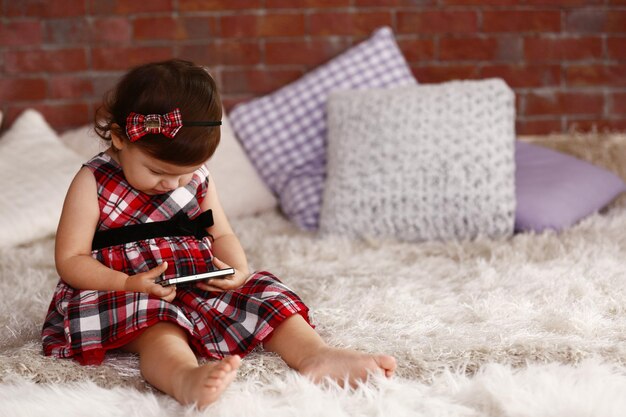 Petite fille regardant un smartphone sur le canapé