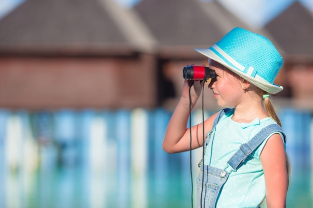 Petite fille regardant à travers des jumelles en journée ensoleillée pendant les vacances d'été