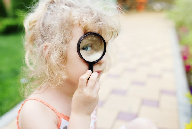 Photo petite fille regardant à travers une loupe