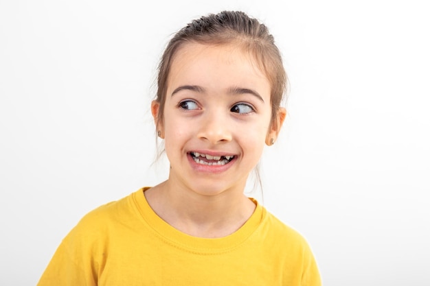 La petite fille regarde de côté, surprise, sur un fond blanc isolé.