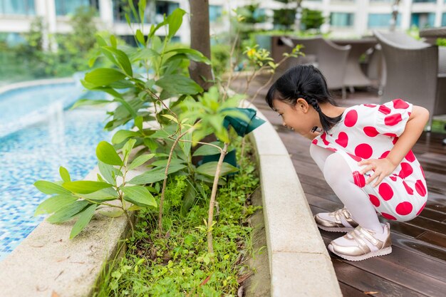 Petite fille regarde le sol dans le jardin