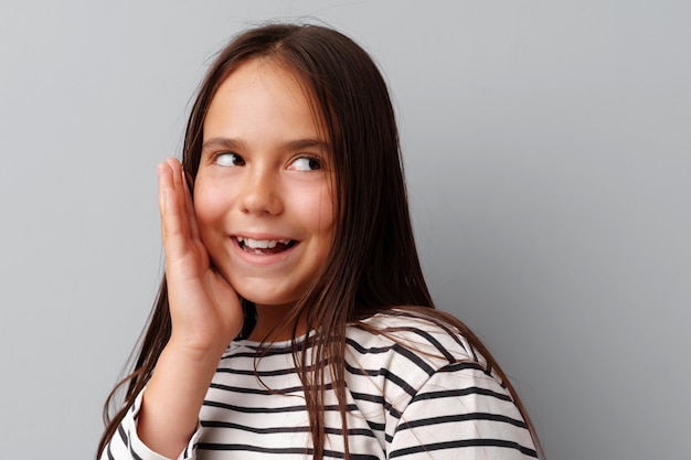 petite fille en riant sur un fond gris