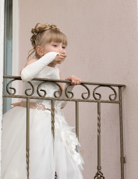 Petite fille en robe de bal sur le balcon