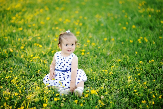 Petite fille en robe blanche assise sur l&#39;herbe