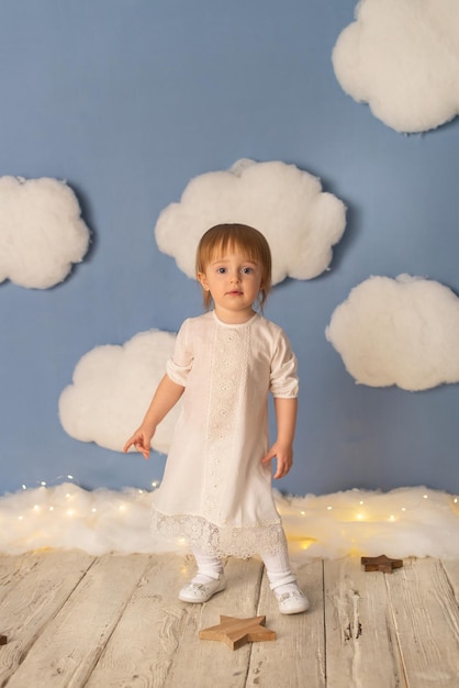 Petite fille en robe blanche sur fond de nuages