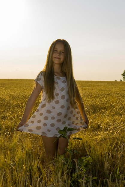 Une petite fille en robe dans un champ de blé