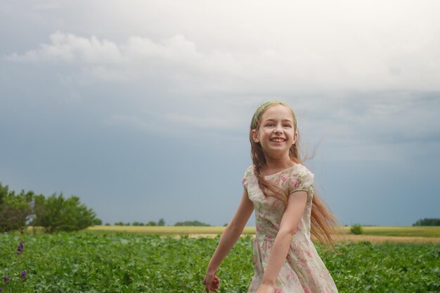 Une petite fille en robe à fleurs sur fond de nature rurale La joie d'un enfant