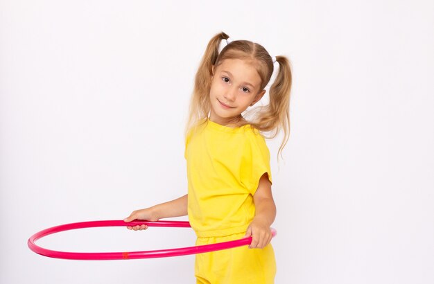 Petite fille en robe jaune tient un cerceau isolé sur une surface blanche