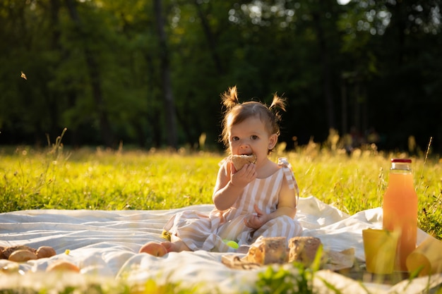 Petite fille en robe rayée sur un pique-nique dans un parc de la ville