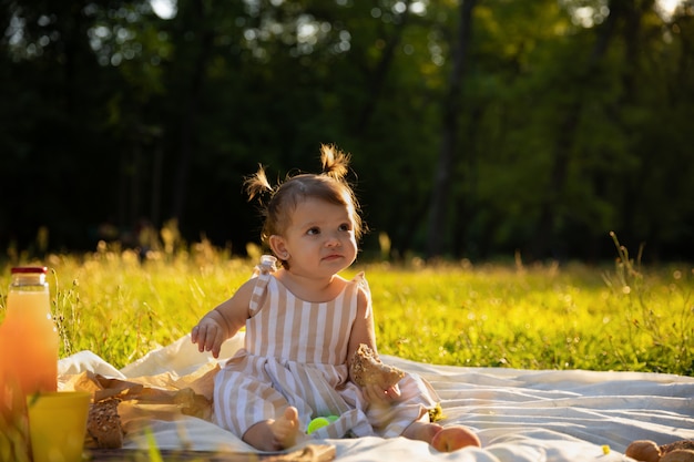 Petite fille en robe rayée sur un pique-nique dans un parc de la ville.