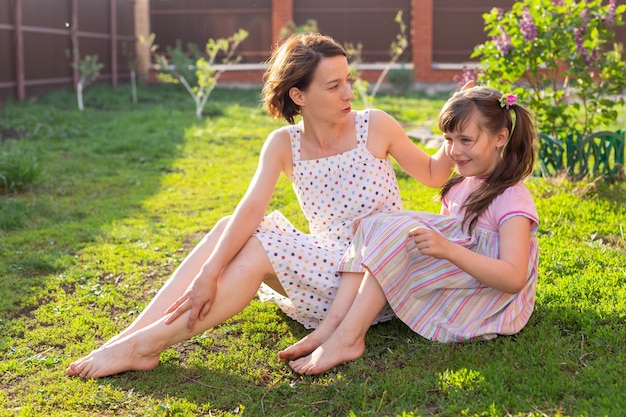 Petite fille en robe rose avec sa mère dans la cour assise sur l'herbe