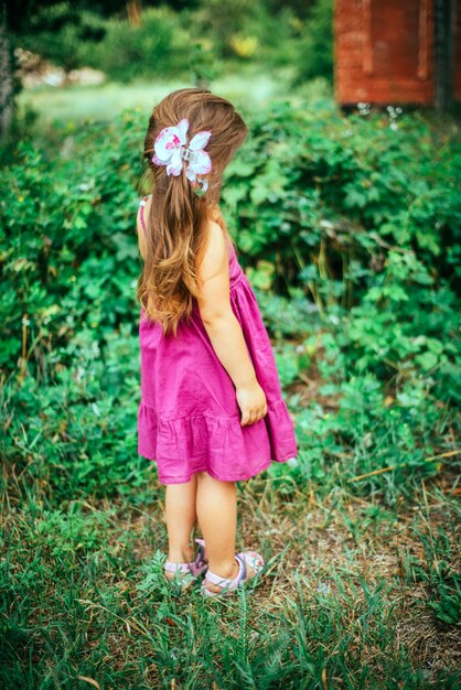 Petite fille en robe rose violette dans la forêt