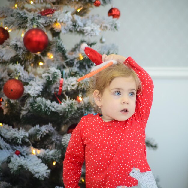 Petite fille en robe rouge jouant dans la chambre avec des décorations de noël