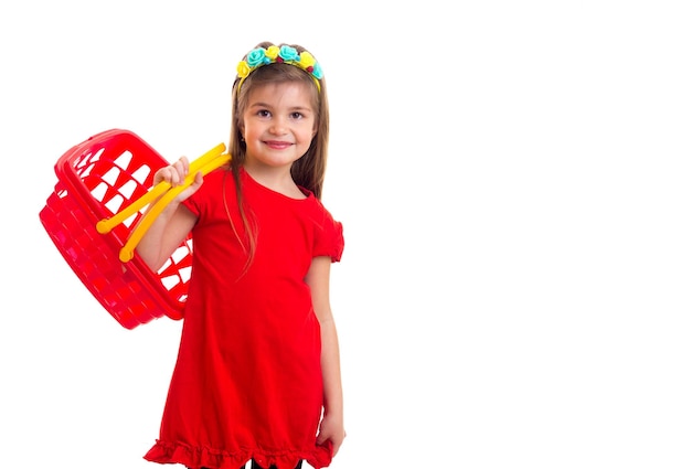 Petite fille en robe rouge avec panier à huis clos à fond blanc