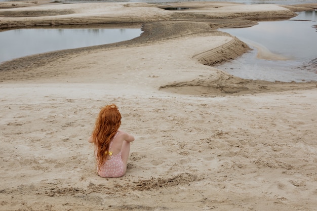 Petite fille rousse jouant sur une plage