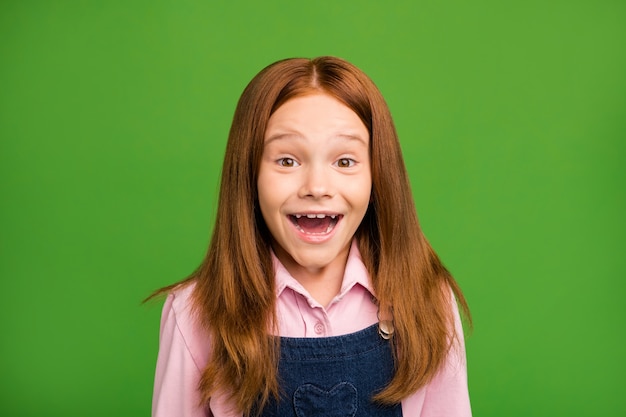 Petite fille rousse posant contre le mur vert