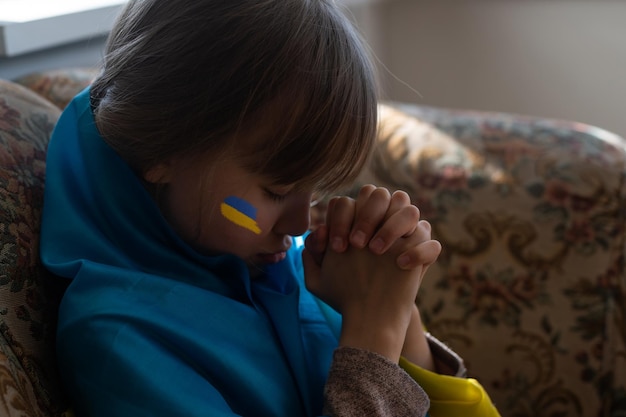 Petite fille avec un ruban de drapeau ukrainien priant Symbole de paix et priez pour l'Ukraine