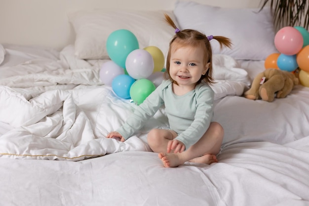 petite fille s'amusant à jouer sur le lit avec des ballons Photo de haute qualité