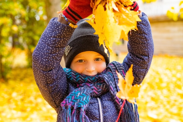 Petite fille s'amusant lors d'une promenade dans la forêt au jour d'automne ensoleillé Enfant jouant des feuilles d'érable