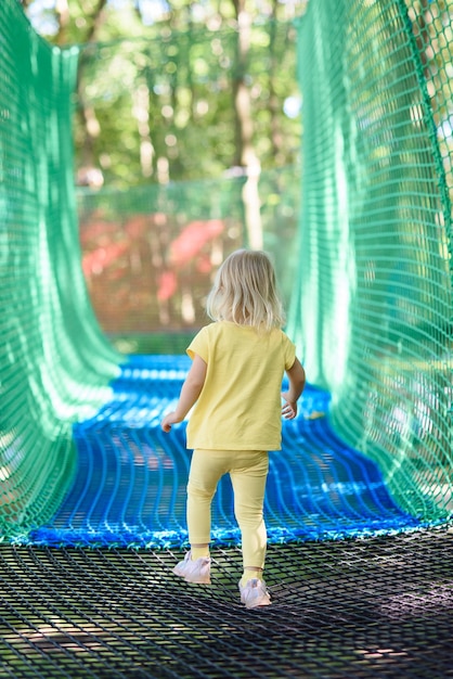 Photo la petite fille s'amuse dans un terrain de jeu de corde. la fille joue sur des cordes de filet.