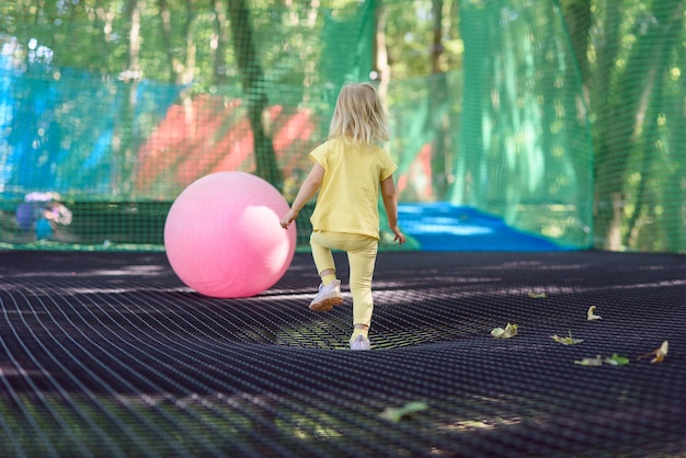 La petite fille s'amuse dans un terrain de jeu de corde. La fille joue sur des cordes de filet.