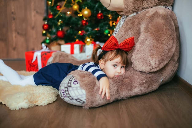 Une petite fille s'amuse à s'allonger sur un ours en peluche offert par le Père Noël pour le décor de Noël Nouvel an