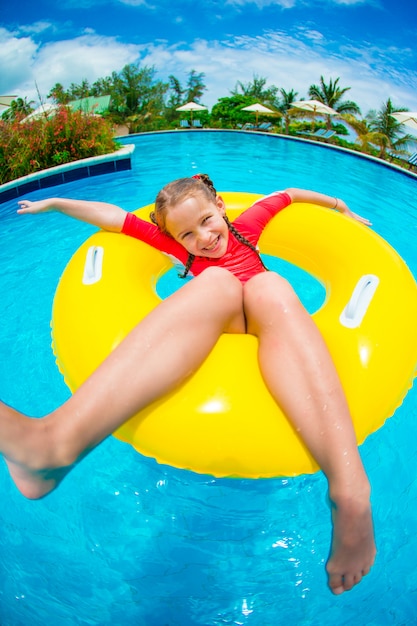 Petite fille s'amuser dans un cercle de caoutchouc gonflable au bord de la piscine. Famille vacances d'été, kid se détendre à la piscine.
