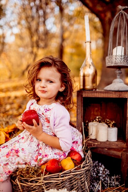 La petite fille s&#39;assoit sur le panier et garde une pomme rouge