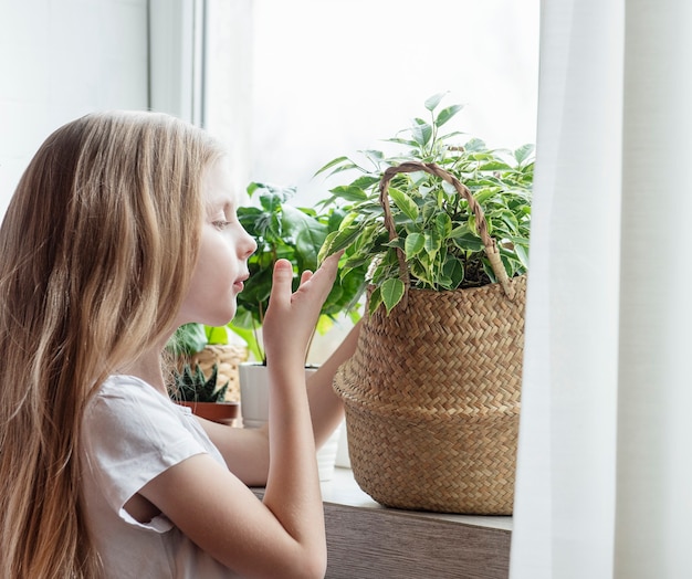 Petite fille s'occupant des plantes d'intérieur à la maison