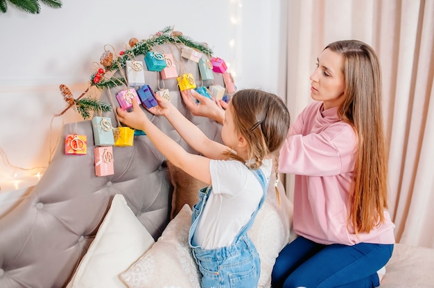 Petite fille avec sa maman examine les cadeaux sur le calendrier de l'avent