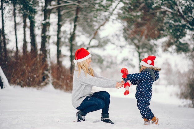 Une petite fille avec sa mère jouant dans un parc d'hiver