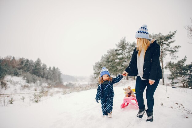 Une petite fille avec sa mère jouant dans un parc d'hiver