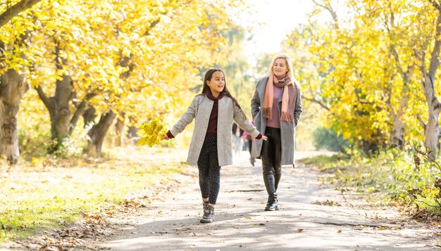 Petite fille et sa mère profitent d'un temps ensoleillé dans le parc d'automne.