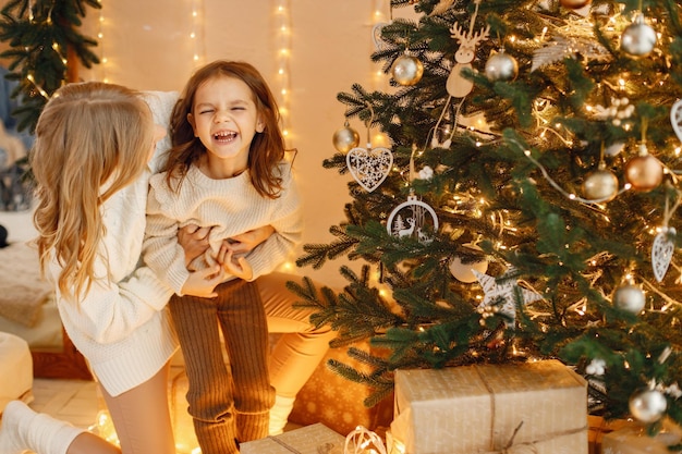 Petite fille et sa mère s'amusent ensemble près du sapin de Noël