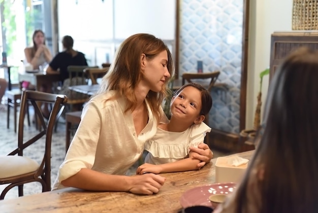 Une petite fille et sa mère s'embrassent et se regardent dans un café.